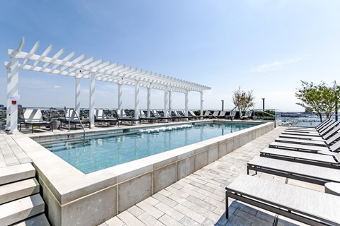 a swimming pool with lounge chairs and a white canopy over it at 1405 Point Street Apartments in Baltimore, MD